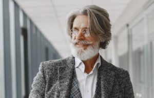 A middle age man with a beard and mustache wearing a very nice gret suit 