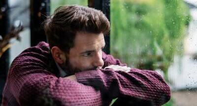 A guy looking glum while resting his head in his arms on a table