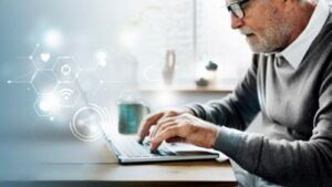 Older man in a grey sweater using a laptop 