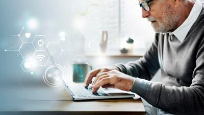 Older man in a grey sweater using a laptop to get google reviews