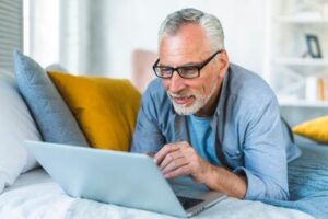man with white beard and glasses working on a laptop